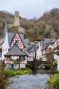 Houses by river against buildings