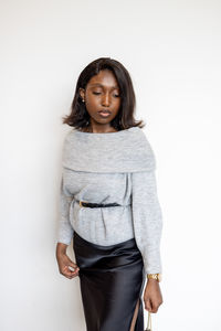 Portrait of young woman standing against white background