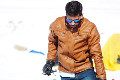 Man wearing leather jacket while standing on snow