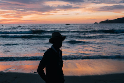 Silhouette man looking at sea against sky during sunset