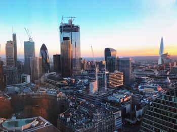 Modern buildings in city against sky during sunset