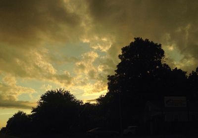 Low angle view of silhouette trees against storm clouds