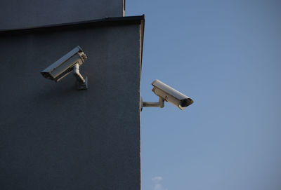 Low angle view of security camera against sky