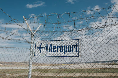 Text on chainlink fence against sky