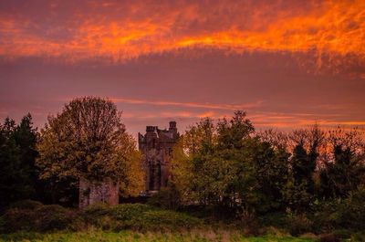 Scenic view of landscape against cloudy sky at sunset