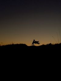 Silhouette man on field against sky during sunset