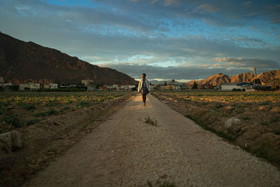 Rear view of man standing on mountain against sky