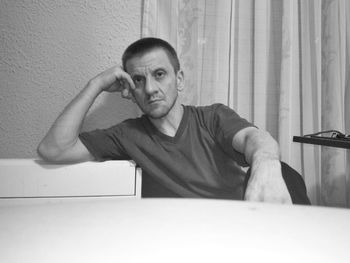 Portrait of man sitting on wall at home