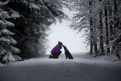 Woman and dog on snow covered landscape