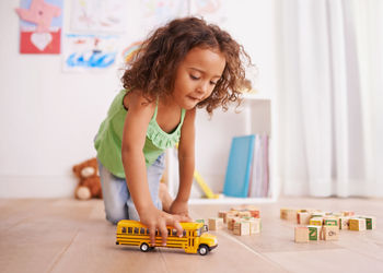 Girl playing with toy bus at home