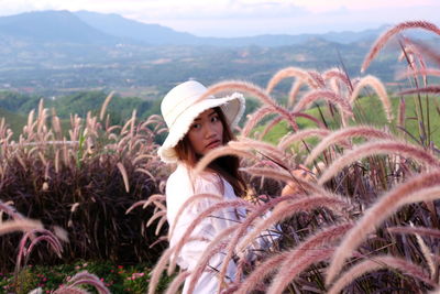 Portrait of woman wearing hat standing amidst plants