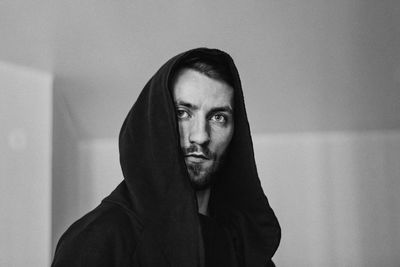 Portrait of young man standing against wall at home