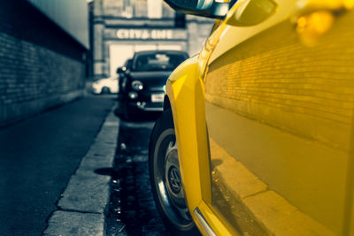 Close-up of yellow car on road