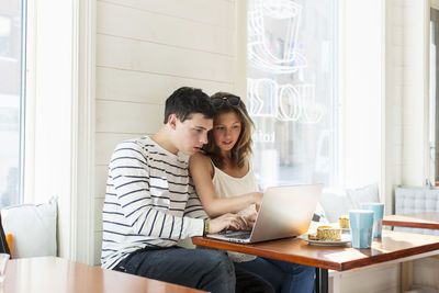 Couple using laptop while sitting at restaurant table