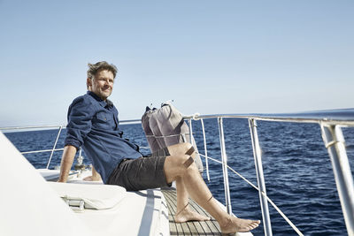 Relaxed mature man sitting on his motor yacht