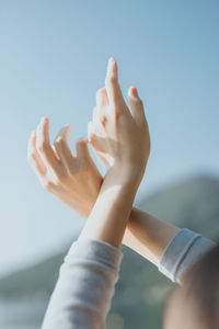 Close-up of hands against sky