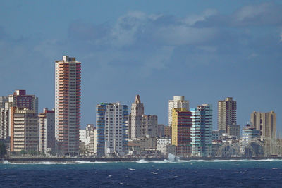 Sea by cityscape against sky