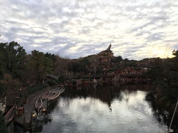 Built structure by river against cloudy sky