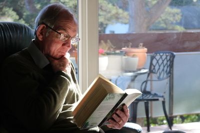 Elderly man reading book at home