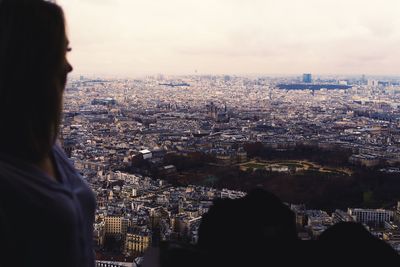 Rear view of woman looking at city buildings against sky