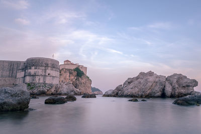 Rock formations by sea against sky