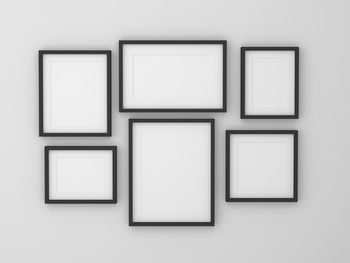 Blank picture frames hanging on white wall