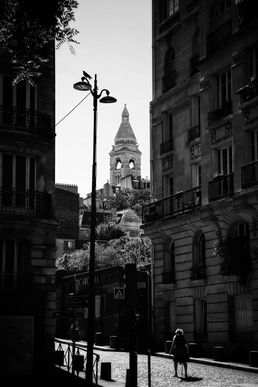 PEOPLE ON STREET BY BUILDINGS AGAINST SKY