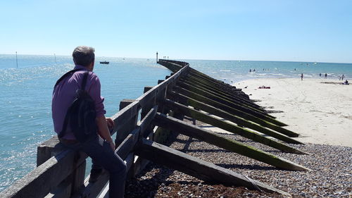 Rear view of man on sea shore against sky