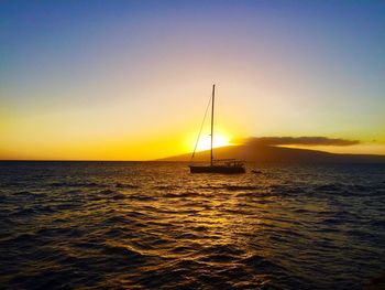 Sailboat sailing in sea at sunset