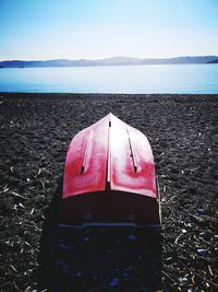 Red boat on sea shore against sky