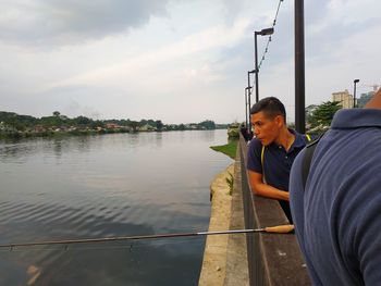 Young man looking at lake against sky