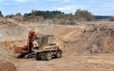 Vehicles at construction site against sky