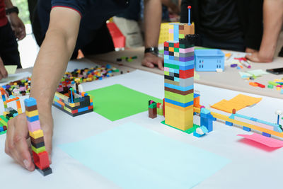 Midsection of people playing with toy blocks on table