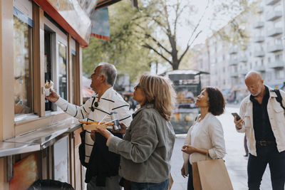 Male and female senior friends buying food store at street