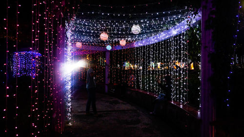 People standing by illuminated lights at night