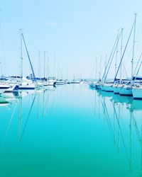 Sailboats moored in sea against clear blue sky