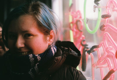 Close-up of young woman smiling by window