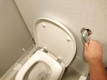 Cropped image of man flushing toilet