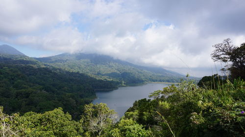 Scenic view of river by mountains against sky