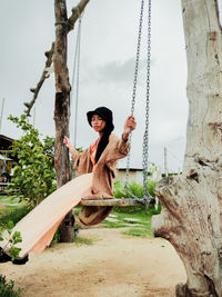 Portrait of young woman on swing at playground