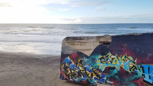 Graffiti on beach against sky