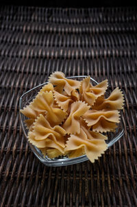 High angle view of raw farfalle pasta in bowl on wicker