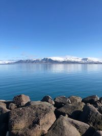 Rocks by sea against blue sky