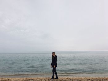 Full length of woman walking on shore at beach against sky