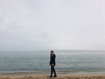 Full length of woman walking on shore at beach against sky