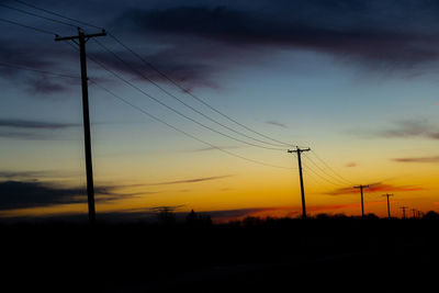 Low angle view of silhouette electricity pylon against sky during sunset