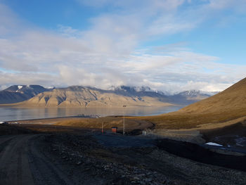 Scenic view of road by mountains against sky