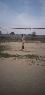 Boy playing on beach against sky