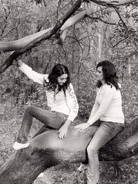 Women standing on field by tree in forest