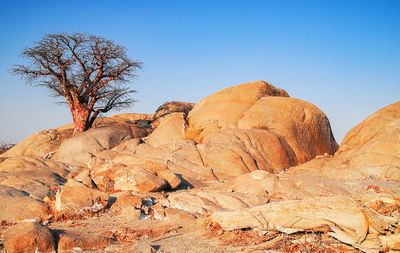 Rock formations on landscape against clear blue sky